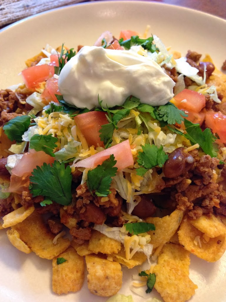 Frito Pie garnished with cheese, tomatoes, sour cream
